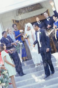 Guests throwing rice at bride and groom in front of church